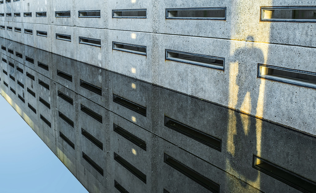Person’s shadow cast across a slatted concrete building facade