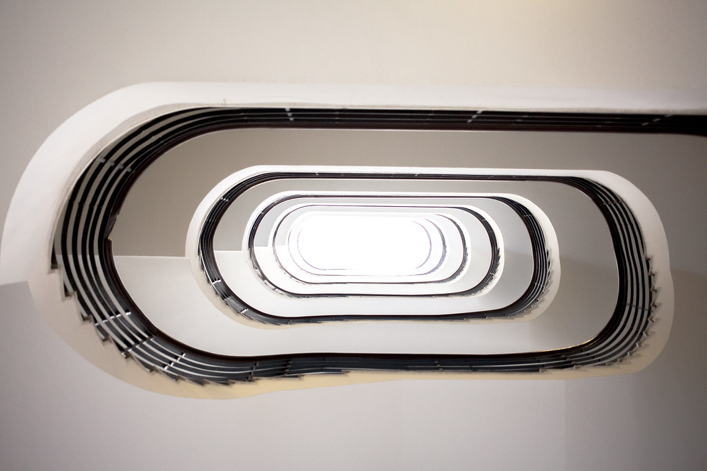Upward view of a spiralling staircase inside a white building