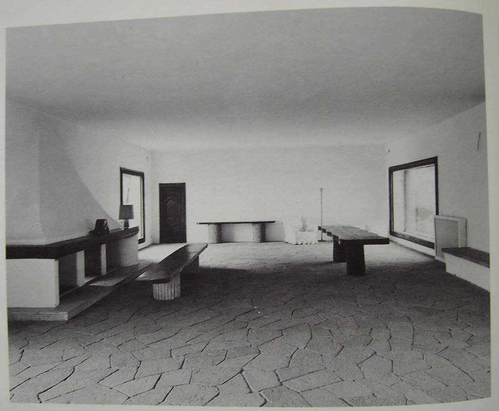 Black-and-white photograph of a furnished lobby with wooden benches